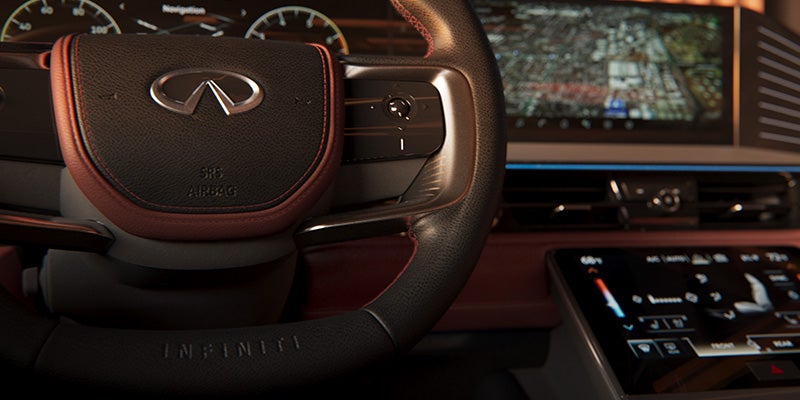 Close-up of an Infiniti interior showing the steering wheel, digital dashboard, and lower climate control screen.
