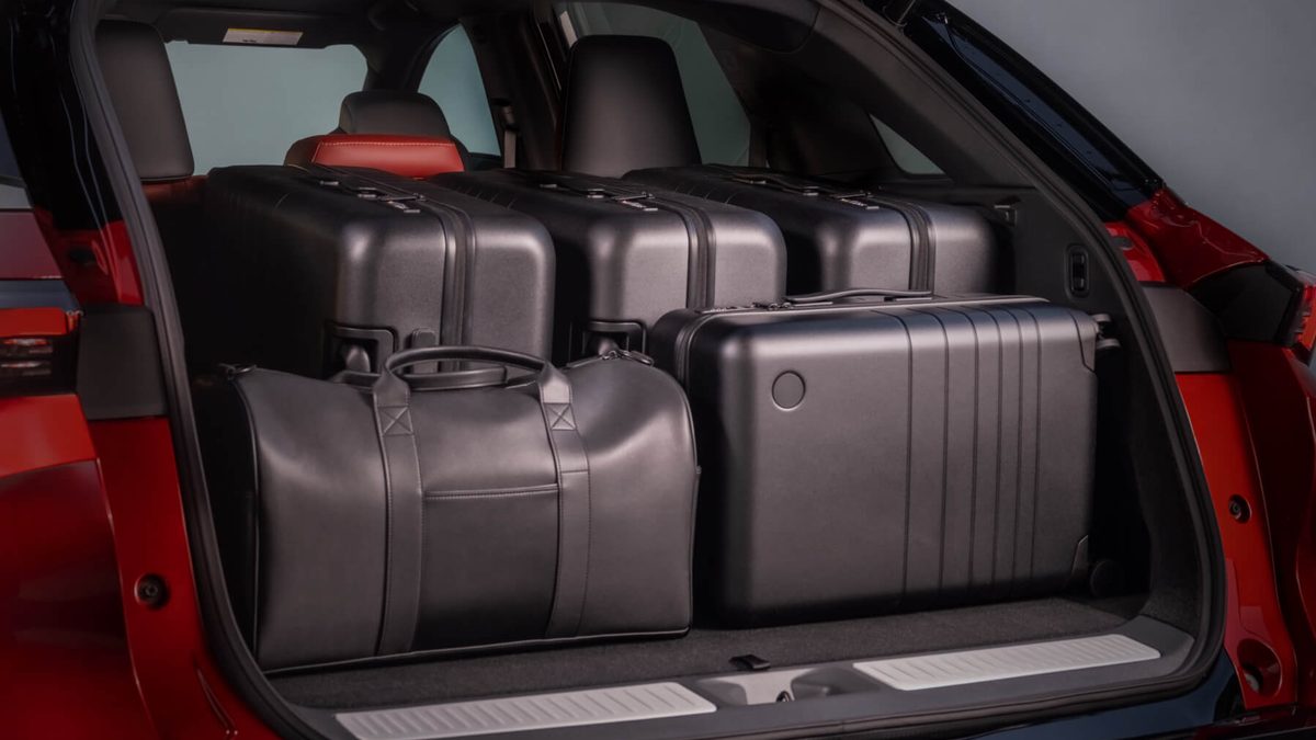 Cargo area of a red 2027 INFINITI QX65 loaded with four hard-shell suitcases and a leather duffel bag