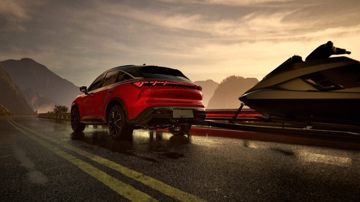 Red 2027 INFINITI QX65 towing a personal watercraft on a wet mountain highway at sunset