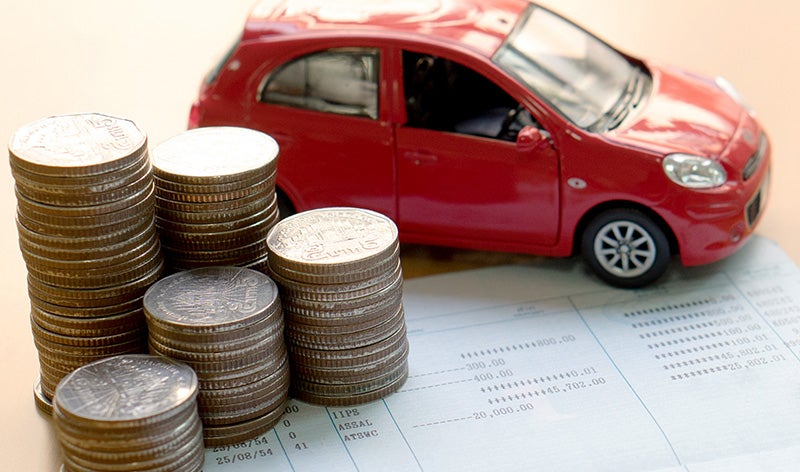 stack of coins and red toy car placed on paper